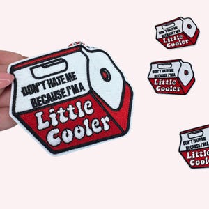 May include: Embroidered patch with a red and white cooler design, the text reads "DON'T HATE ME BECAUSE I'M A Little Cooler." The patch has a black border and is designed for clothing or accessories.