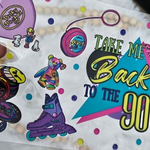 Peut inclure: Une collection d'autocollants color&eacute;s sur le th&egrave;me des ann&eacute;es 90. Comprend un sac Polly Pocket, un yo-yo, un ours en peluche arc-en-ciel, un patin &agrave; roulettes violet et l'expression "Take Me Back To The 90s."