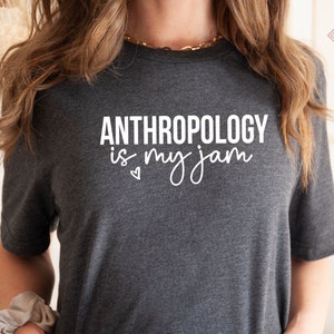 May include: A dark grey t-shirt with the text "ANTHROPOLOGY is my jam" in white lettering. A small heart is printed below the text.