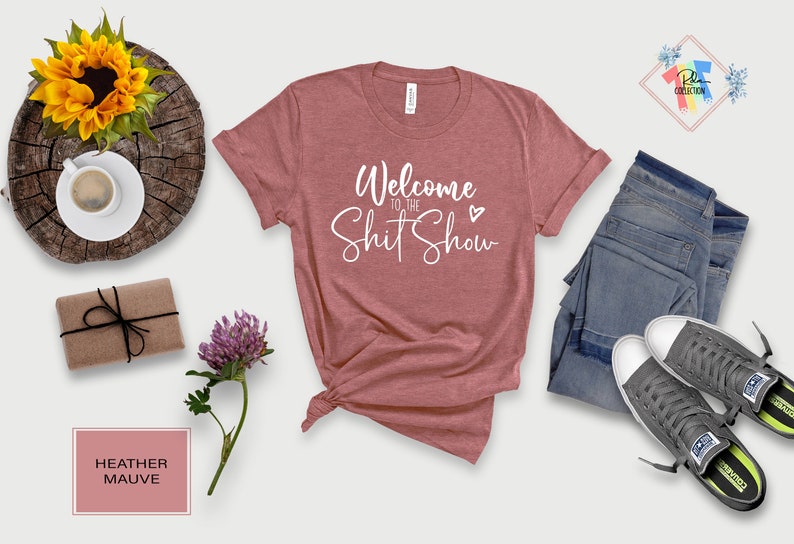 May include: Heather mauve t-shirt with the text "Welcome to the Shit Show" in white cursive lettering with a small white heart.