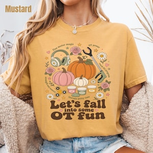 May include: A mustard yellow t-shirt featuring a graphic print with pumpkins, flowers, headphones, a reacher grabber tool, and therapy putty containers. The text reads: fine motor magic, OT power, reach for progress, strength and sensory, therapy putty time, Let's fall into some OT fun.