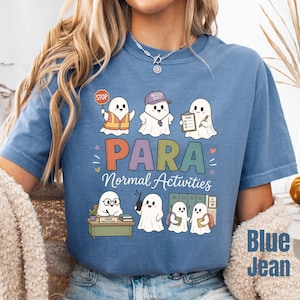 May include: A blue t-shirt featuring a graphic of several white ghosts performing various school-related tasks. The text reads "PARA Normal Activities". The ghosts are depicted with items like a stop sign, a whistle, a clipboard, a desk, and backpacks.