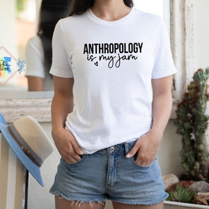 May include: White t-shirt with black text that reads "Anthropology is my jam" with a small heart symbol.