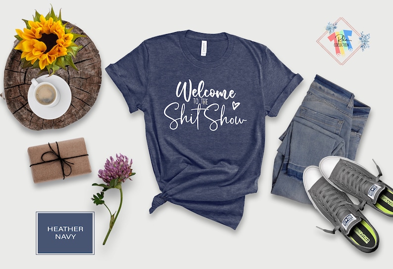 May include: A heather navy blue t-shirt with the text "Welcome to the Shit Show" in white cursive lettering with a small heart.