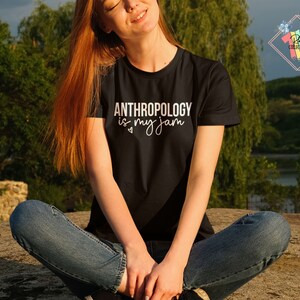 May include: A woman wearing a black t-shirt with the text "ANTHROPOLOGY is my jam" in white lettering. The shirt has a heart symbol next to the word "my".