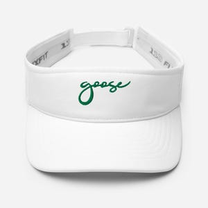 May include: A white visor featuring the word goose embroidered in green cursive script on the front panel. The visor includes an adjustable back strap with a white buckle and interior branding that reads 110 FLEXFIT on the inner band.