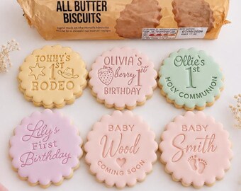May include: Six round, scalloped-edge cookies with pastel icing and embossed text. Designs include Tommy's 1st Rodeo, Olivia's Berry 1st Birthday, Ollie's 1st Holy Communion, Lily's First Birthday, Baby Wood Coming Soon, and Baby Smith with footprints.