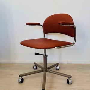 May include: A vintage office chair with a brown upholstered seat and back, chrome arms, and a five-star base with wheels.