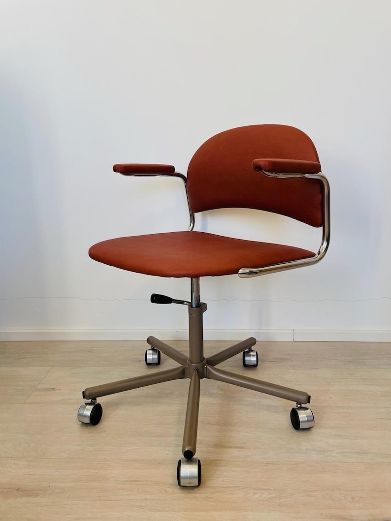 May include: A vintage office chair with a brown upholstered seat and back, chrome arms, and a five-star base with wheels.
