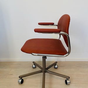 May include: A brown leather office chair with chrome arms and a five-star base with wheels.
