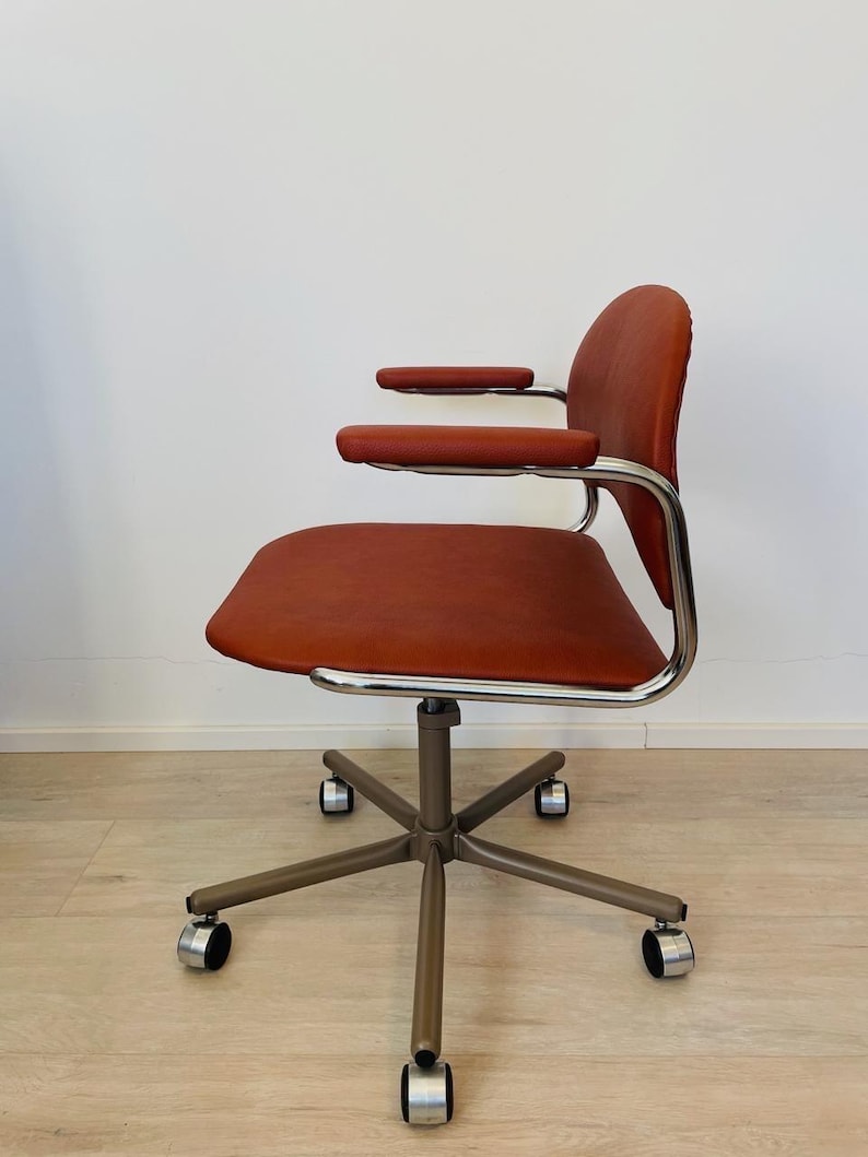 May include: A brown leather office chair with chrome arms and a five-star base with wheels.