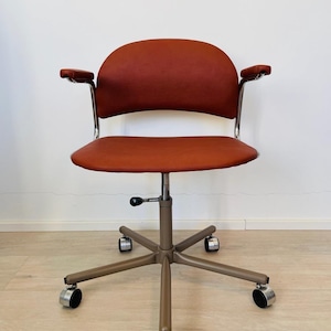 May include: A red office chair with adjustable height and five wheels. The chair has a curved back and armrests.