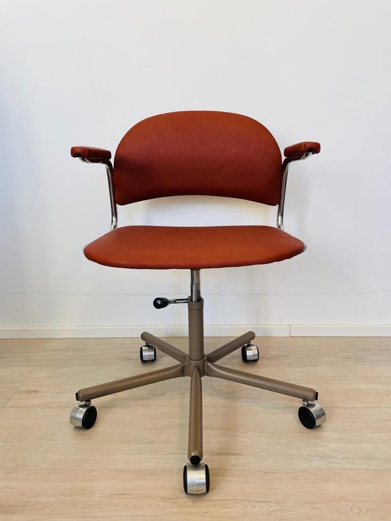 May include: A red office chair with adjustable height and five wheels. The chair has a curved back and armrests.