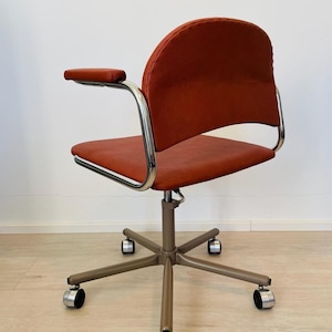 May include: A red office chair with chrome arms and a swivel base with five wheels. The chair has a padded seat and back.