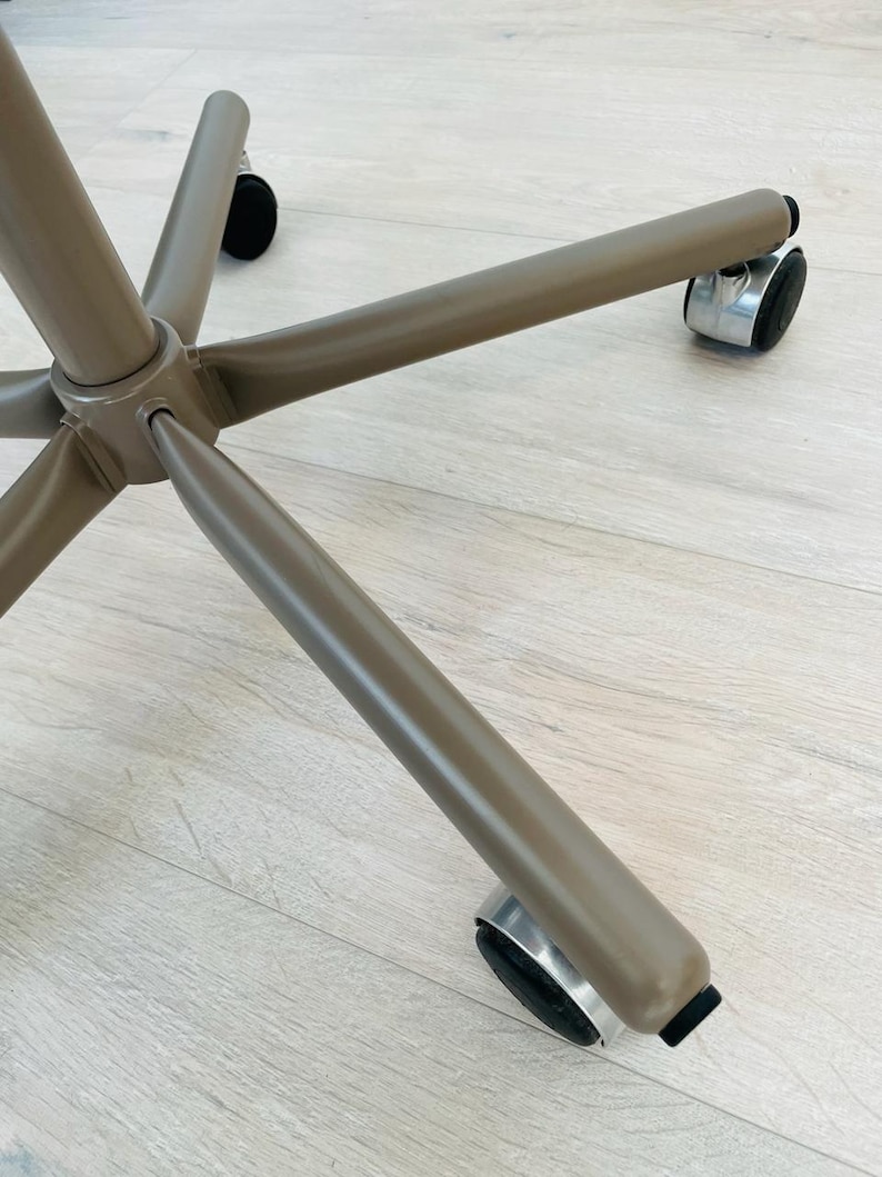 May include: A brown metal office chair base with five wheels. The wheels are made of black rubber and have a silver metal rim.