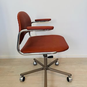 May include: A brown leather office chair with chrome arms and a silver base with five wheels.