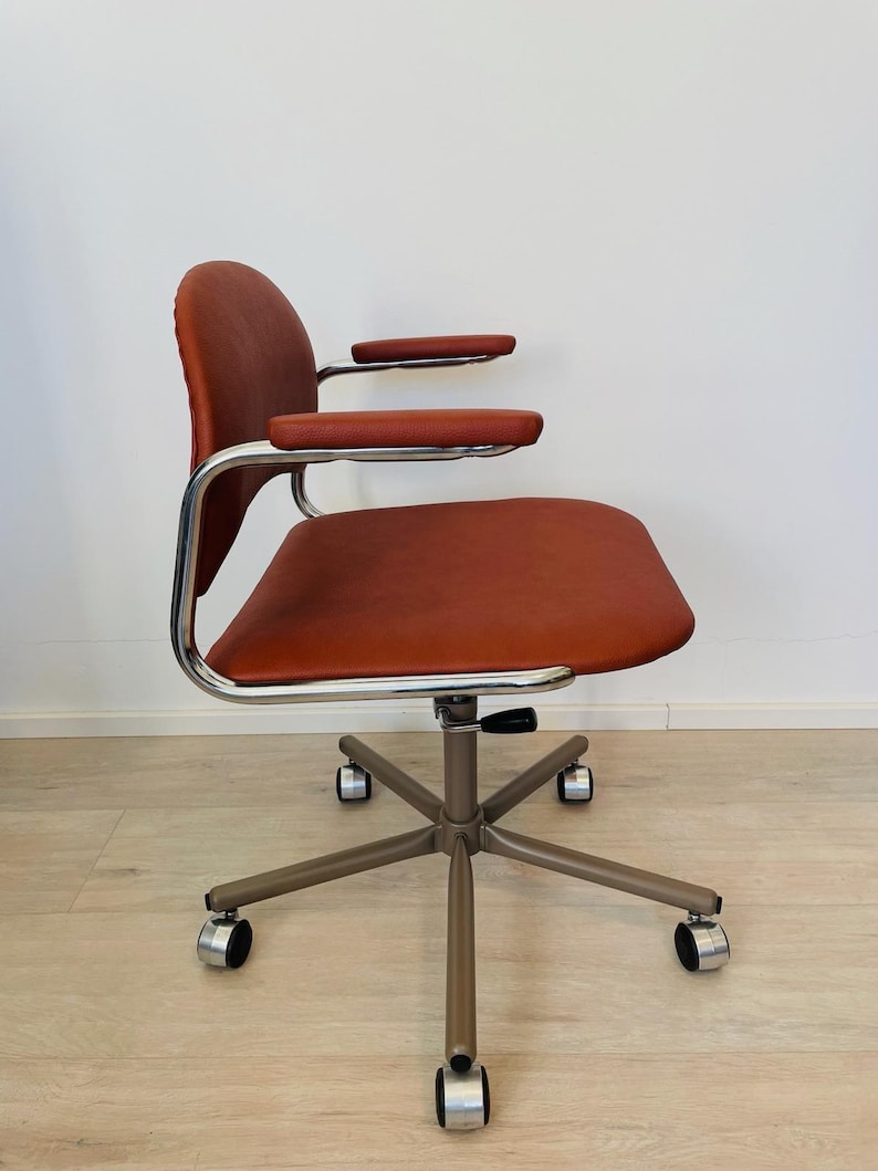 May include: A brown leather office chair with chrome arms and a silver base with five wheels.