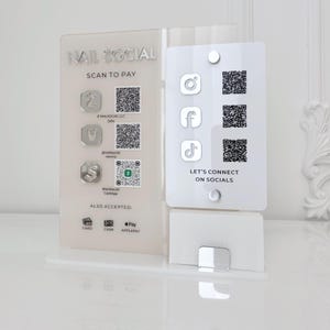 Puede incluir: Un letrero de acrílico transparente para Nail Social con el texto "NAIL SOCIAL" y "SCAN TO PAY". Presenta códigos QR para pago y redes sociales, junto con los métodos de pago aceptados. El letrero está diseñado para colocarse de pie.