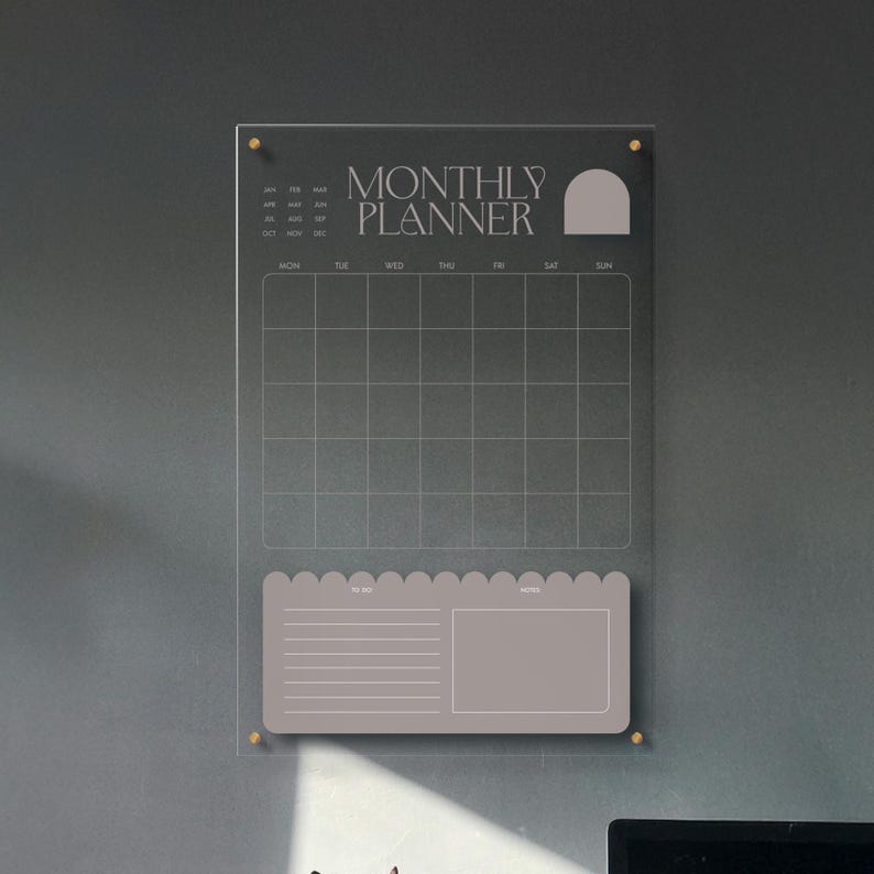 May include: A clear acrylic monthly planner with gold-colored hardware. The planner features a grid for scheduling, a section for to-do lists, and the words "MONTHLY PLANNER" in a serif font.
