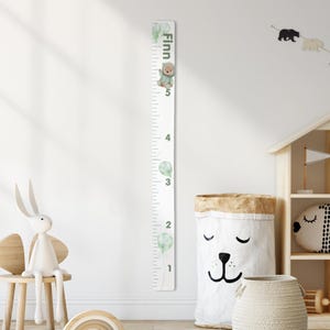 May include: A white height chart with green watercolor balloons and a teddy bear illustration. The chart measures up to 5 feet. The name "Finn" is printed at the top.