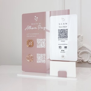 Op de afbeelding: Een roze en witte acryl point-of-sale display. De display toont de tekst "BEAUTY BY Allison Paige" en "LET'S CONNECT ON SOCIALS". Het bevat ook een QR-code en de woorden "SCAN TO PAY". Geaccepteerde betaalmethoden worden vermeld.