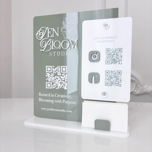 以下が含まれることがあります： 「Jen Bloom Studio」と「Let's Connect on Socials」の文字が入った、白とセージグリーンの名刺ホルダー。InstagramとFacebookのQRコードとソーシャルメディアアイコンが含まれています。ベースは白です。