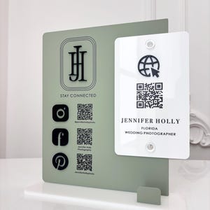Puede incluir: Un moderno tarjetero con un diseño verde salvia y blanco. Presenta iconos de redes sociales, códigos QR y el texto "STAY CONNECTED" y "JENNIFER HOLLY FLORIDA WEDDING PHOTOGRAPHER". El soporte es de acrílico.