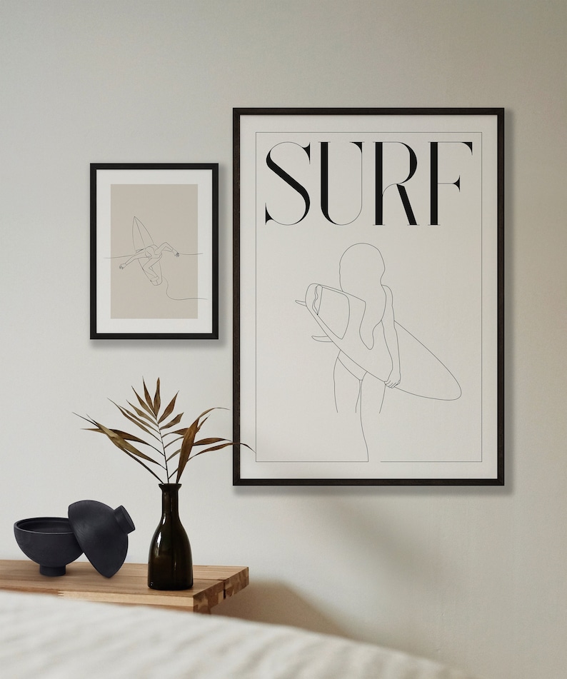 May include: Two black framed prints with line drawings of a person surfing. The larger print has the word "SURF" in bold letters at the top. The smaller print shows a person surfing a wave.
