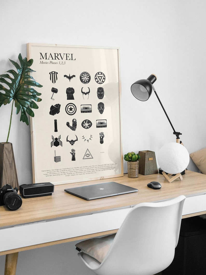 May include: A black and white poster with the word "MARVEL" in large letters at the top. Below the title, it says "Movies Phases 1, 2, 3". The poster features a grid of 24 black and white icons representing different characters and objects from the Marvel Cinematic Universe.