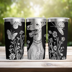 May include: Three black stainless steel travel mugs with silver lids. Each mug has a white illustration: one with butterflies and flowers, one with a dog, and one with a butterfly and flowers. The mugs are on a wooden surface.