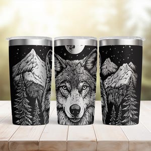 May include: Three stainless steel travel mugs with a black background. Each mug features a detailed black and white illustration of a wolf, mountains, trees, a full moon, and stars. The mugs have a silver rim and lid.