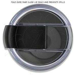 May include: A clear plastic lid with a black snap closure. The lid has a dark interior and a black clasp with the letter "Z". The text "FOLD OVER SNAP CLOSE LID SEALS AND PREVENTS SPILLS" is visible.