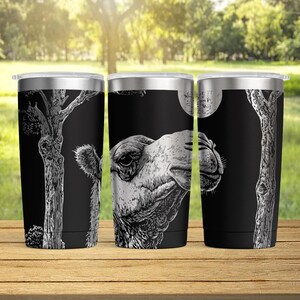 May include: Three stainless steel travel tumblers with black backgrounds. Each tumbler features a white illustration of a tree or a camel's head. The center tumbler shows a full moon. The tumblers are on a wooden surface.