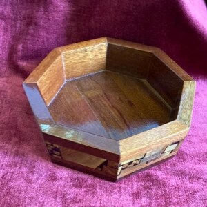 Peut inclure: Bol en bois octogonal avec un motif d'incrustation géométrique dans des tons de brun, noir et blanc.
