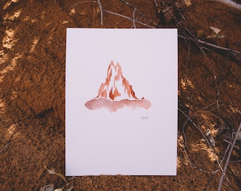 May include: A watercolor painting of a mountain range in shades of brown and orange. The painting is on a white background and is signed "zlon" in the bottom right corner.