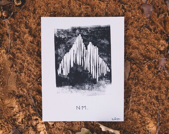 May include: A black and white print of a mountain range with the text "NM." and the year "2020" in the bottom right corner.
