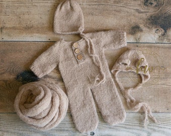 May include: A brown knitted baby outfit with a matching hat and a wrap. The outfit has a button closure and the hat has a long tie.
