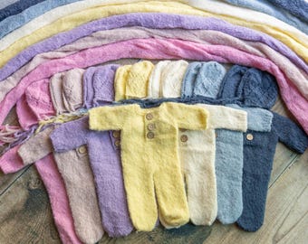 May include: A set of ten knitted baby outfits in various colors, including pink, purple, yellow, white, and blue. Each outfit features a long-sleeved jumpsuit with a hood and button closures.