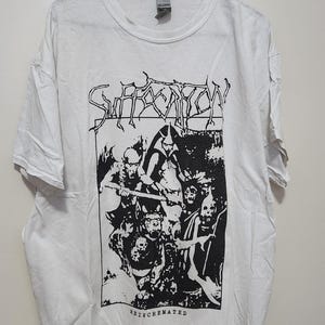 May include: White t-shirt featuring a black and white graphic print of a band called "Suffocation" with the text "Re-Incarnated" beneath the graphic.