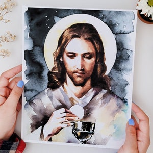 Puede incluir: Pintura acuarela de Jesucristo sosteniendo un c&aacute;liz y una hostia. Est&aacute; representado con cabello largo casta&ntilde;o y barba, vistiendo una t&uacute;nica gris claro. El fondo es azul oscuro con un halo alrededor de su cabeza.