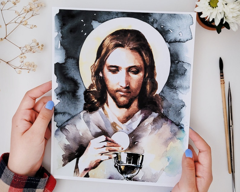 Puede incluir: Pintura acuarela de Jesucristo sosteniendo un c&aacute;liz y una hostia. Est&aacute; representado con cabello largo casta&ntilde;o y barba, vistiendo una t&uacute;nica gris claro. El fondo es azul oscuro con un halo alrededor de su cabeza.