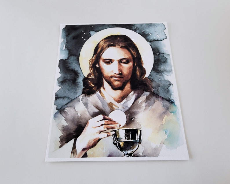 Puede incluir: Una pintura de acuarela de Jesucristo sosteniendo una copa y una hostia. La pintura est&aacute; sobre un fondo oscuro con un halo de luz alrededor de la cabeza de Jes&uacute;s.