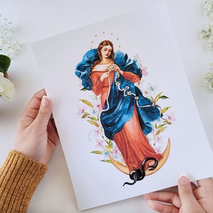 May include: A watercolor painting of the Virgin Mary, depicted with a blue robe and red dress, standing on a crescent moon. She is holding a rope in her hands, and there are white flowers surrounding her.