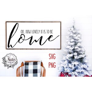 Puede incluir: Un letrero de madera blanco con texto negro que dice "Oh, how lovely it is to be home". El letrero está colgado en una pared blanca con un pequeño árbol de Navidad blanco a la derecha.