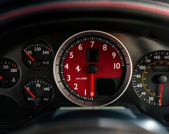 May include: A black car dashboard with a red and black tachometer, a speedometer, and two smaller gauges. The tachometer reads up to 10,000 rpm and has a red needle pointing to 5,000 rpm. The speedometer reads up to 220 mph and has a red needle pointing to 100 mph. The smaller gauges are for temperature and fuel level.