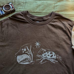 snail and beetle blockprint t-shirt | entymology/bug-themed lino print clothing | starry celestial vibes with cute insect design