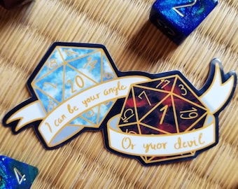 May include: Two dice stickers with gold foil accents. The blue die has white clouds and the text "I can be your angle". The red die has black flames and the text "Or your devil".