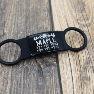 May include: Black dog tag with a mountain and trees design, the name "MAPLE" and phone numbers 123 456 7890 and 098 765 4321.