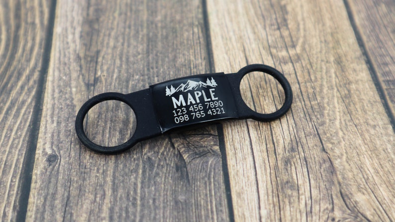 May include: Black dog tag with a mountain and trees design, the name "MAPLE" and phone numbers 123 456 7890 and 098 765 4321.