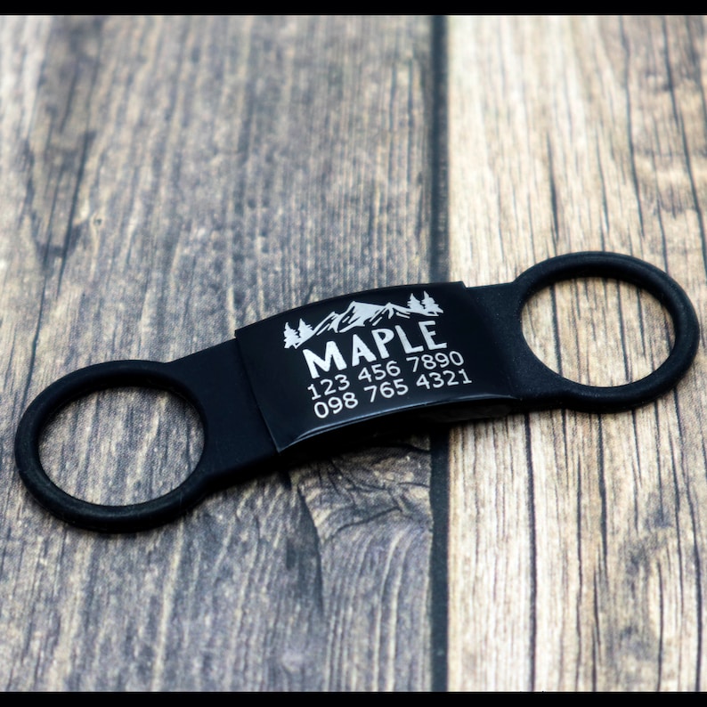 May include: Black dog tag with a silver engraved mountain scene and the text "MAPLE 123 456 7890 098 765 4321".